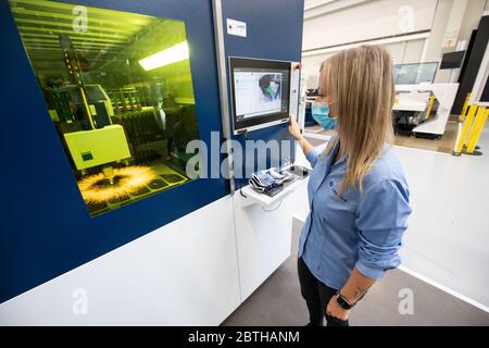 Ditzingen, Germania. 26 Maggio 2020. Un dipendente del produttore di macchine Trumpf gestisce una macchina da taglio laser nel centro dimostrativo dell'azienda. Indossa una maschera sopra la bocca e il naso. (A dpa 'l'ingegneria meccanica nel sud-ovest disegna il primo equilibrio corona') Credit: Marijan Murat/dpa/Alamy Live News Foto Stock