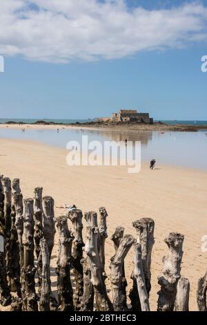 La gente sulla spiaggia sabbiosa e la vista del mare con il Fort National in background, Bretagna Francia Foto Stock