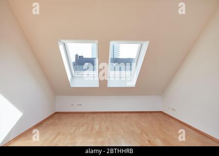 Camera vuota con finestra e soffitto spiovente con parquet in appartamento mansarda Foto Stock