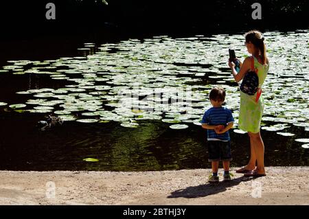 Una madre e suo figlio a Queensmere Pond a Wimbledon Common, Londra, Regno Unito Foto Stock