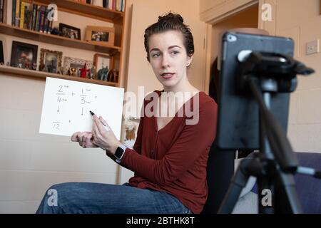 Gli insegnanti della scuola sono costretti ad insegnare le loro lezioni da casa online virtualmente utilizzando i loro telefoni per video se stessi sotto covid-19 coronavirus UK USA Foto Stock