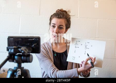 Gli insegnanti della scuola sono costretti ad insegnare le loro lezioni da casa online virtualmente utilizzando i loro telefoni per video se stessi sotto covid-19 coronavirus UK USA Foto Stock