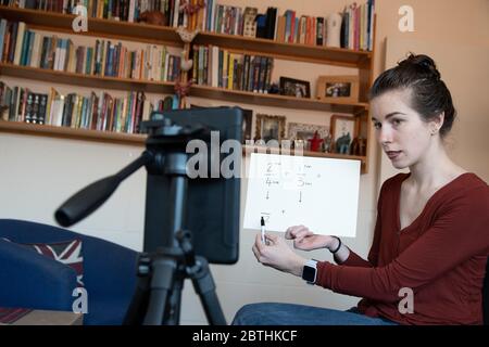 Gli insegnanti della scuola sono costretti ad insegnare le loro lezioni da casa online virtualmente utilizzando i loro telefoni per video se stessi sotto covid-19 coronavirus UK USA Foto Stock