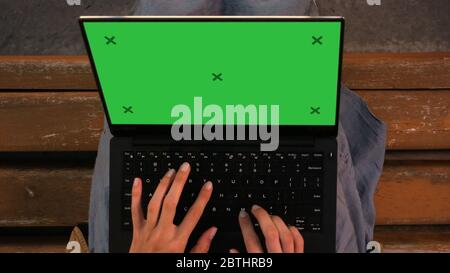 Donna che scrive su un computer portatile seduto su una panca. Foto Stock