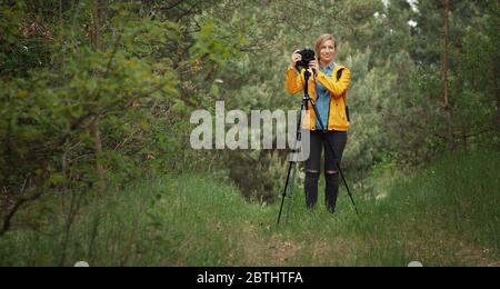 Fotografo in piedi in una foresta verde Foto Stock