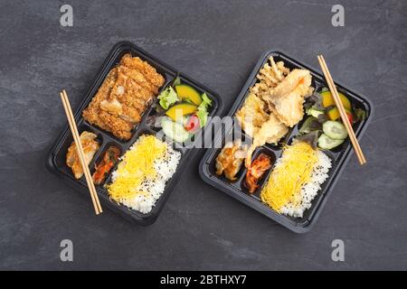 Il cibo giapponese bento si presenta con tonkatsu e tempura su sfondo di pietra scuro Foto Stock