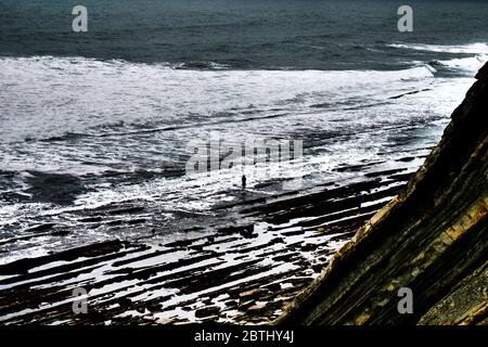 Lone pescatore sulla costa rocciosa vicino Socoa - digitale filtrato vista, regione basca, costa atlantica, Pirenei Atlantici, Nouvelle-Aquitaine, Francia sud-occidentale Foto Stock