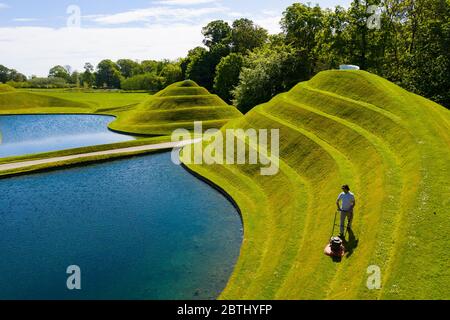 Wilkieston, Scozia, Regno Unito. 26 maggio 2020. Thomas Unterdorfer, custode del paesaggio a Giove Artland, tagliando l'erba sulle sculture in terraferma celle di vita di Charles Jencks. Jupiter Artland spera di avere un'apertura limitata nel prossimo futuro, quando le regole di blocco di Covid-19 sono rilassati. Iain Masterton/Alamy Live News Foto Stock