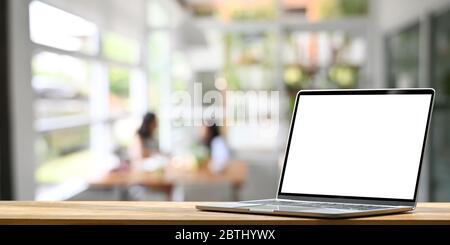 Foto di bianco schermo bianco computer portatile mettere su bancone bar di legno su un ristorante confortevole e clienti come sfondo. Foto Stock