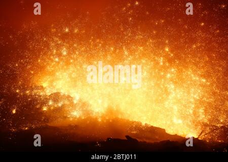 Scintille volano da metallo fuso caldo in forno a grandi opere d'acciaio Foto Stock