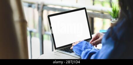 Immagine ritagliata delle mani della donna che scrivono su bianco schermo computer portatile bianco che mettere su banco di legno vintage barra sopra balcone vista come b Foto Stock