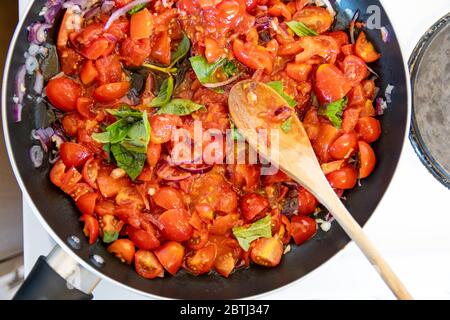 Deliziosa salsa di pomodoro e basilico fatta in casa sul piano cottura, che simmering e cuocendo Foto Stock