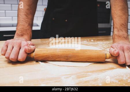 Primo piano di un impasto per arrotolare le mani dell'uomo Foto Stock