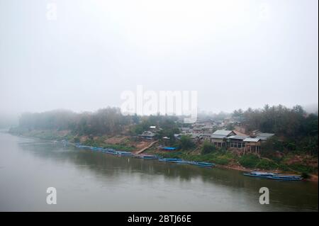 Barche lente di legno sul fiume Mekong durante una mattina nebbiosa, Laos settentrionale, Asia sudorientale Foto Stock