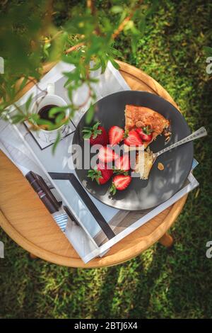 Torta fatta in casa con fragole servite sotto un albero in giardino Foto Stock