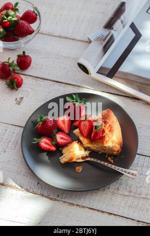 Una fetta di torta fatta in casa con fragole fresche su un tavolo di legno bianco Foto Stock