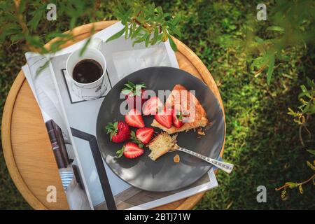 Una fetta di torta fatta in casa con fragole servita in un giardino girato dall'alto Foto Stock