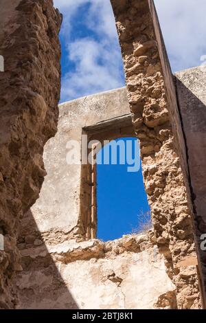 Muri rotti e tetto di una rovina di una casa abbandonata. Vista dall'interno dell'edificio. Finestra rotta e cielo blu luminoso. Dar Caid Hadji (usato al Foto Stock