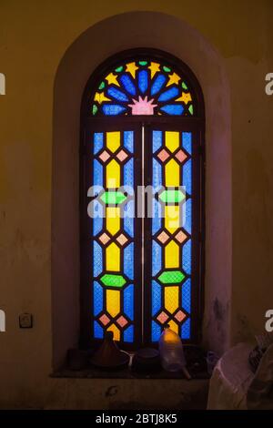 Parte ben conservata di un complesso abbandonato. Interno di una camera con finestra con vetrata colorata e cornice in legno. Dar Caid Hadji (usato anche Hajji Foto Stock