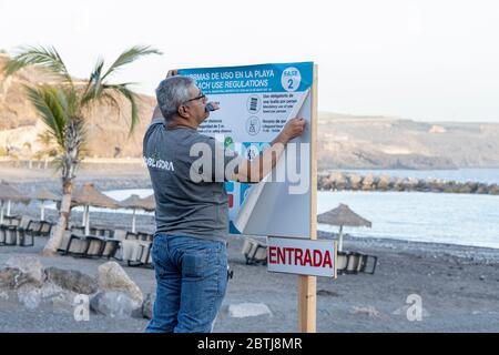 Uomo che mette in su avviso bilingue con le regole di uso della spiaggia durante la fase due della de-escalation dello stato di emergenza, covid 19, coronavirus lockdow Foto Stock