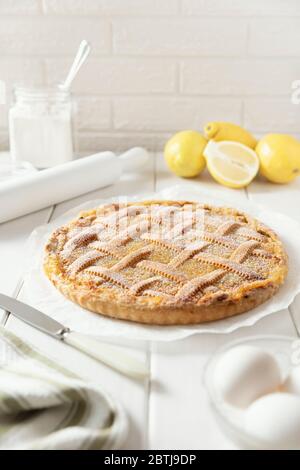 Torta di limoni di shortbread fatta in casa con un motivo di vimini cosparsa di zucchero in polvere. Ingredienti per una torta: Farina in un vaso di vetro, limoni, uova. Foto Stock