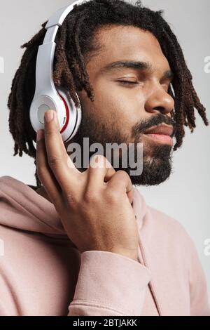 Ritratto di un uomo afro-americano soddisfatto utilizzando cuffie wireless isolate su sfondo bianco Foto Stock