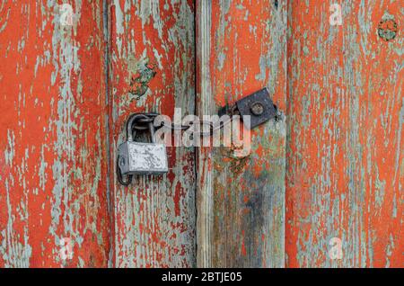 Vecchia porta in legno chiusa da un lucchetto primitivo su catena Foto Stock