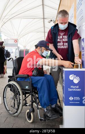 I pendolari utilizzano un punto di igienizzazione per le mani alla stazione degli autobus di Stratford. Londra, Regno Unito. Maggio 2020 Foto Stock