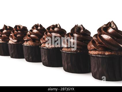 Deliziosi cupcake al cioccolato con sparkles d'oro cosparsi di glassa al cioccolato fiancheggiata diagonaly su sfondo bianco isolato. Mockup per il tuo design. Foto Stock