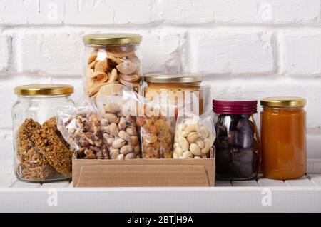 Set di lungo termine di stoccaggio prevalentemente cibi dolci energia secca su scaffale dispensa su sfondo muro di mattoni Foto Stock