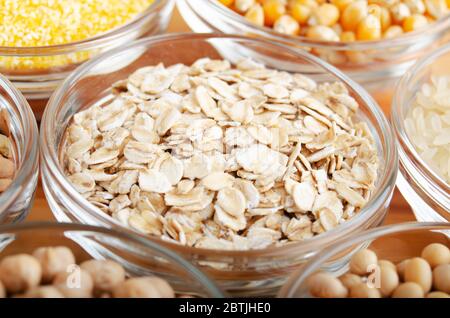 Rolled oat flakes closeup in vetro recipiente su tavola di legno cucina, non deperibile, concetto di cibo a lunga durata di conservazione Foto Stock