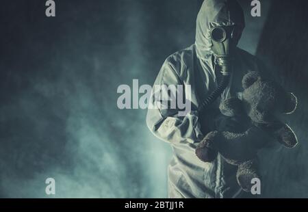 Concetto post apocalittico. Virus Outbreak combattente lavoratore in maschera militare di rischio biologico e Hazmat vestito con Teddy Bear ha trovato in Dark Deep Forest Foto Stock