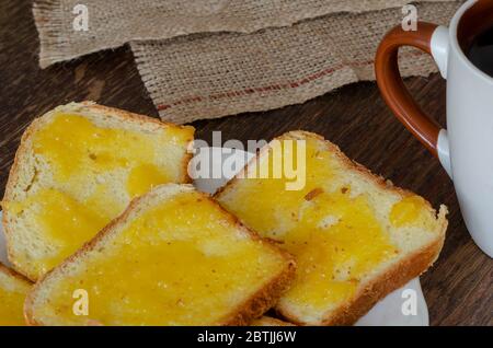 Fette di pane con miele di tiglio su fondo di legno scuro. Piatto con panini dolci. Una tazza di caffè sullo sfondo. Cibo fatto in casa. SID Foto Stock