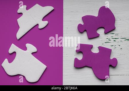 Frammenti del puzzle su uno sfondo lilla. Puzzle bianco e blu non assemblati. Salute psicologica e pensiero logico. Vista dall'alto. Foto Stock