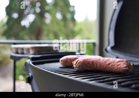 A base di piante oltre le salsicce di carne sulla griglia. Fuoco selettivo su una delle estremità della salsiccia vegana. Foto Stock