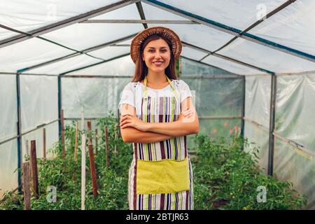 Donna contadina in serra. Felice lavoratore coltivando verdure che lavorano in serra. Agricoltura Foto Stock