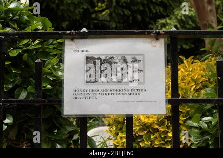 un cartello appeso su una recinzione del parco che dice che le api del miele stanno lavorando in questo giardino per renderlo ancora più bello, sostenendo l'ecosistema con i pollinatori Foto Stock