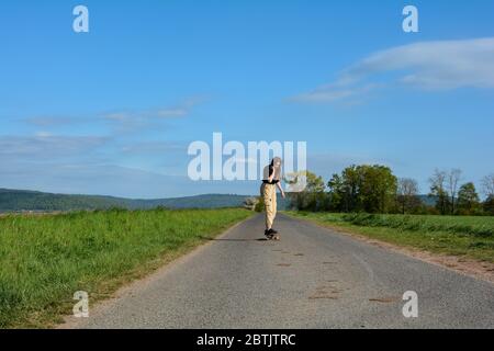 La ragazza corre su una strada di campagna in natura verde, cielo blu e copia Foto Stock