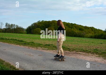 Una ragazza sul lato, fa un giro su una strada di campagna in natura verde Foto Stock