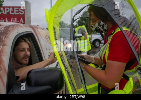 Manhattan, Kansas, Stati Uniti. 25 Maggio 2020. JAYLEE LAYTON, a destra, prende un ordine da NICKOLAS OATLEY, a sinistra, a Chick-fil-a mentre indossa una capanna impermeabile durante una tempesta di pioggia il Memorial Day. Credit: Luke Townsend/ZUMA Wire/Alamy Live News Foto Stock