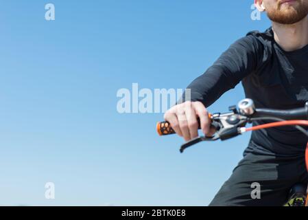 Ciclista che guida una bicicletta su una strada aperta al tramonto Chioseup ritratto di un atleta di ciclista con la bearded. All'aperto. Sport primaverili. Il ragazzo ha venticinque anni Foto Stock