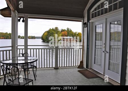Vista sul lago dal balcone del cottage. Attraverso l'acqua è un cottage immerso tra alberi verdi Foto Stock