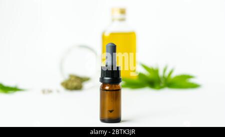 Bottiglie di vetro con olio essenziale CBD, foglie di marijuana medica, boccioli e semi su sfondo bianco, primo piano. Concetti di alternativa o di erbe medici Foto Stock