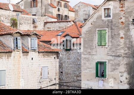 Donna croata leggermente nascosta nella finestra di casa sua mentre guarda il suo cellulare, Città Vecchia, Spalato, Croazia Foto Stock