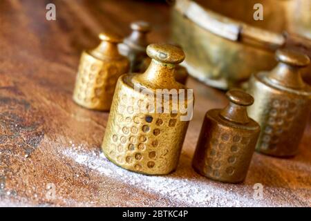 Pesi in rame vecchio con segni di taratura su tavola di legno con farina in panificio. Immagine con messa a fuoco selettiva. Foto Stock