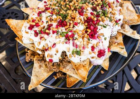 Un piatto di manzo e di melanzana fatteh, un piatto tradizionale medio orientale di pezzetti tostati di pane piatto con melanzane e manzo e yogurt Foto Stock