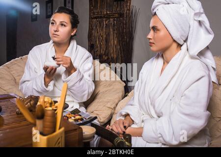 Cerimonia del tè dopo la sauna. Le ragazze in cappotti bianchi bevono tè cinese. Foto Stock