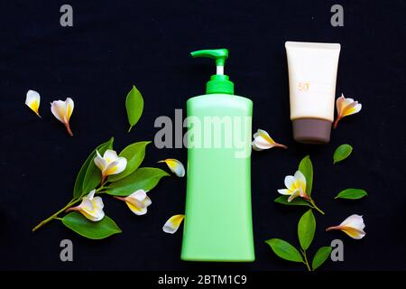 crema solare spf50 cosmetici cura della salute per la pelle viso, lozione corpo e fiori gialli frangipani di stile di vita donna relax in estate stagione Foto Stock