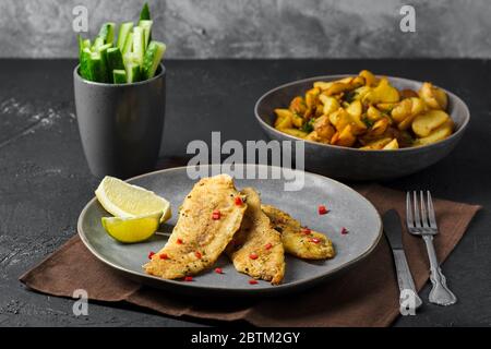 Filetto di nasello fritto con spezie e spicchi di patate arrostiti Foto Stock