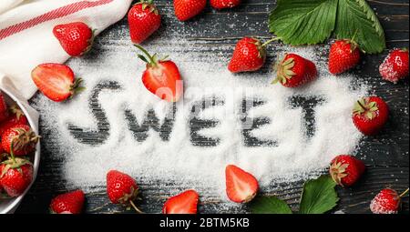 Parola dolce fatto di zucchero, e fragola su sfondo di legno, vista dall'alto. Bacche estive Foto Stock